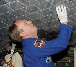Astronaut Andy Thomas takes a close look at a Space Shuttle tile. Credit: NASA