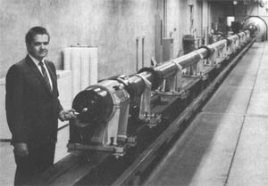 Light-gas gun. Thomas N. Canning holds model that is fired down range. Plastic pistons are seen stacked against wall at left. Credit: NASA