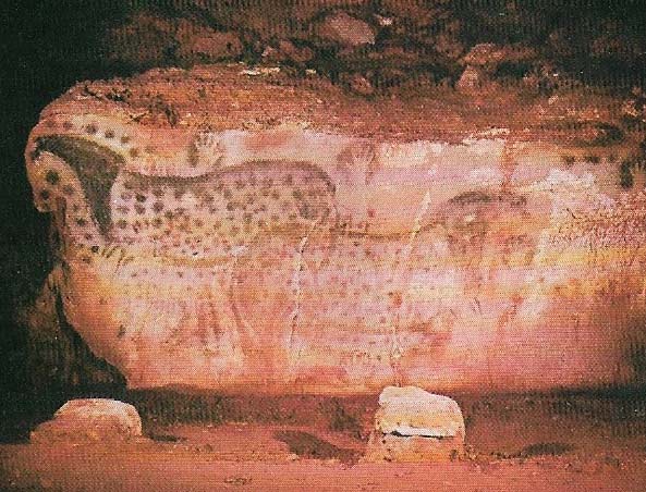 A wall of the cave of Pech-Merle in France shows two spotted horses with more spots surrounding them and heads and necks in solid color.