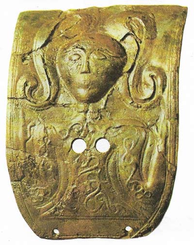 An early example of La Tene art style is shown here. The bronze plaque from a double burial at Waldalgesheim (c. 325 BC) shows a mask-like face, a torque round the neck and, on the head, traces of a leaf-crown which is a token of divinity. The hands are raised in the Celtic attitude of prayer. This bronze is one of a pair.