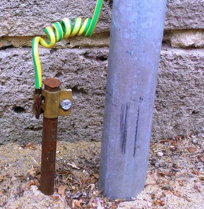 A typical earthing electrode (left of gray pipe), consisting of a conductive rod driven into the ground.